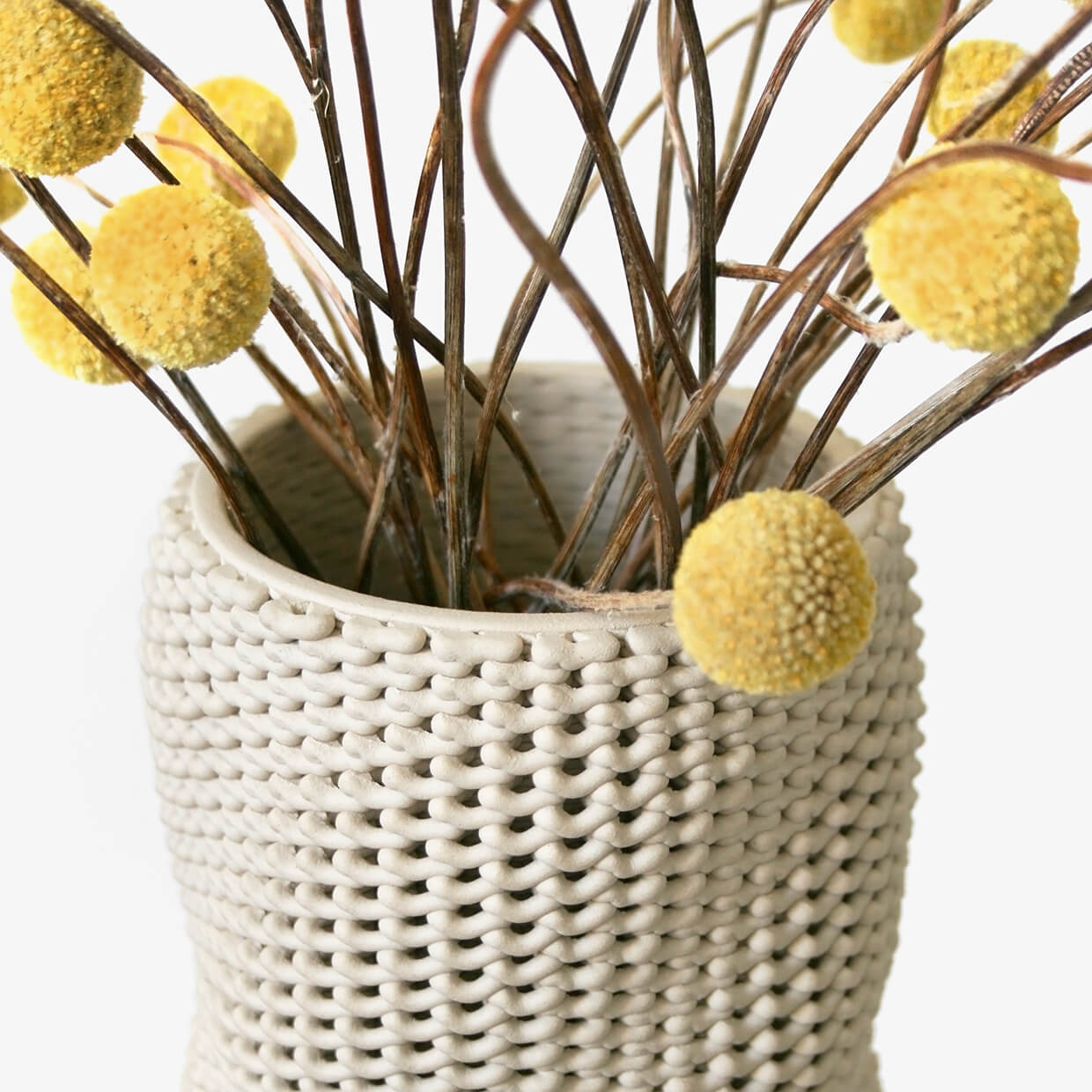 Close-up of Kilim holding yellow flowers. A 3D printed ceramic vase by Drag And Drop on a white background