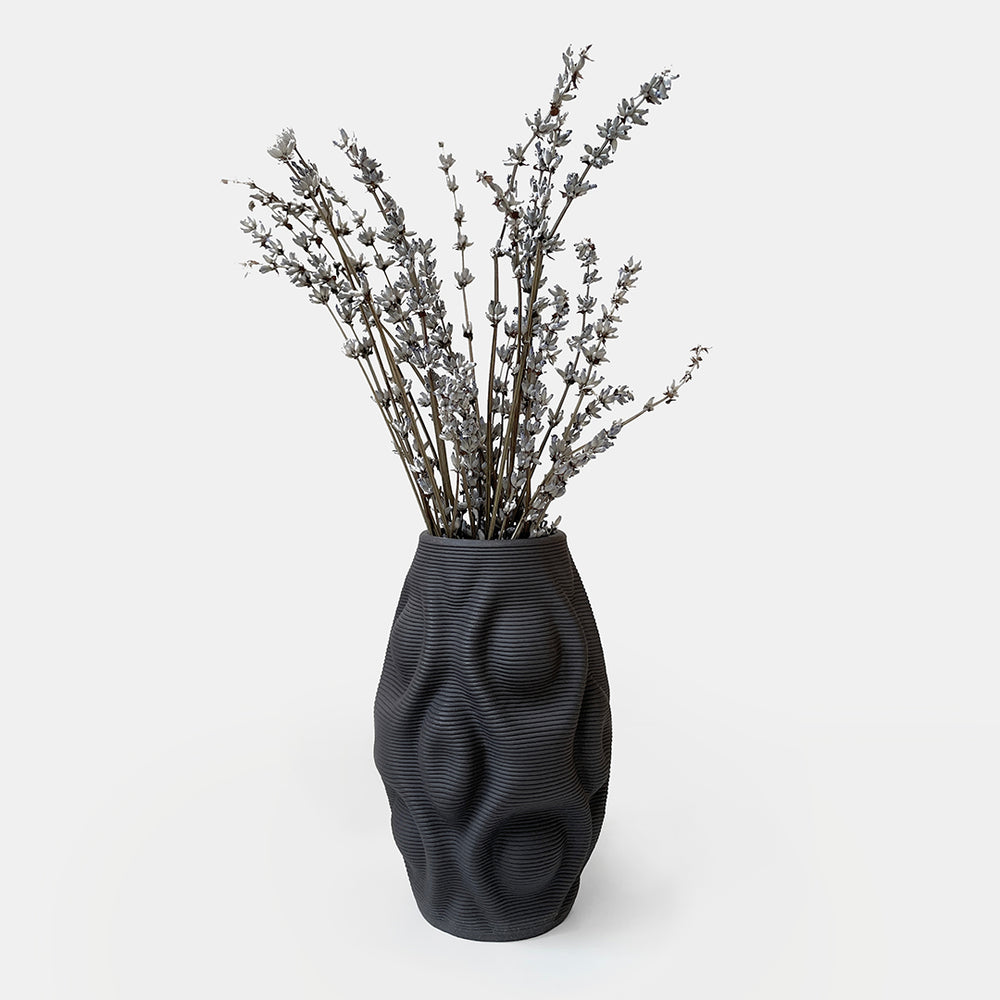 The vase's design features a curvaceous body, mimicking the gentle flow of water. It showcases organic ripples that undulate gracefully, evoking a sense of movement and fluidity. The shape is derived from mathematical formulas, meticulously translated into a 3d printed ceramic vase.